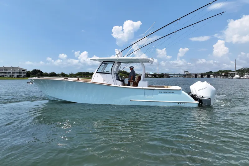 Slide: The Image of 2023 Phenom 34 boat on water, clear sky, fishing rods, Mercury engines. - 3