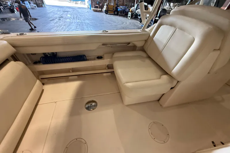Slide: The Image of 2021 Grady-White Freedom 275 boat interior with beige seating in a warehouse setting. - 18