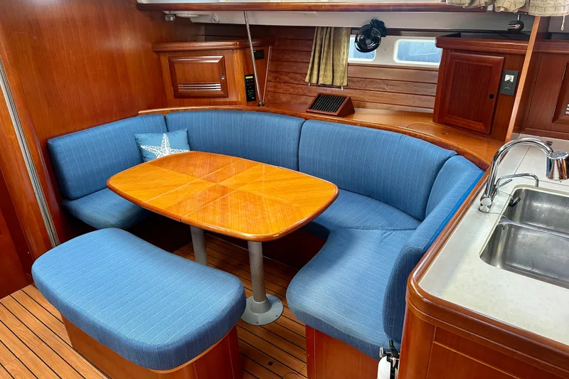 Slide: The Image of Interior of 2002 Beneteau Oceanis Clipper 473 with blue seating and wooden table. - 24
