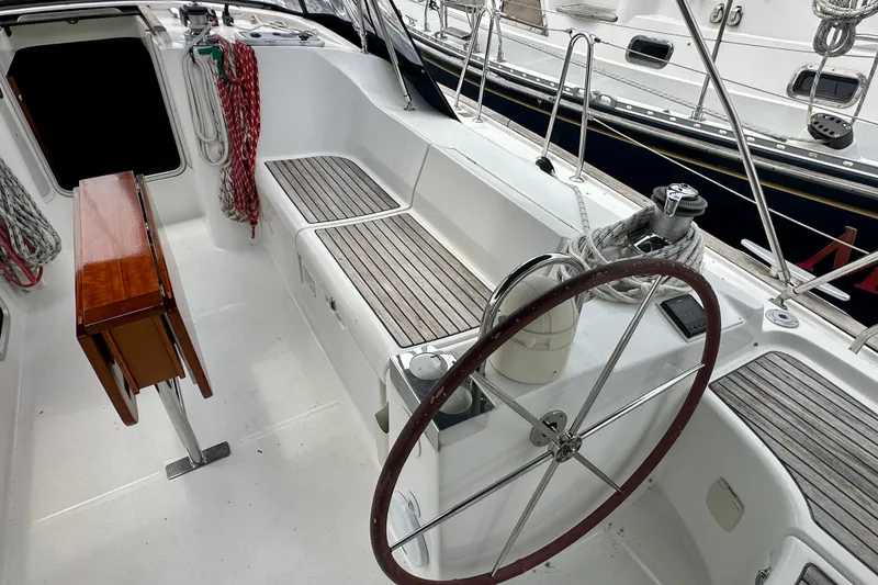 Slide: The Image of Cockpit of 2002 Beneteau Oceanis Clipper 473 sailboat with wooden seating and steering wheel. - 12