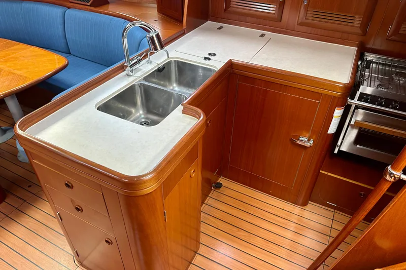 Slide: The Image of Interior of 2002 Beneteau Oceanis Clipper 473 yacht, featuring a wooden galley with sink and stove. - 26