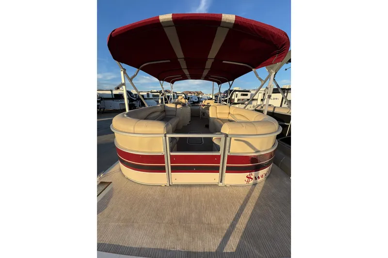 Slide: The Image of 2010 Bennington 2375RL pontoon boat with red canopy and beige seating, docked under blue sky. - 8