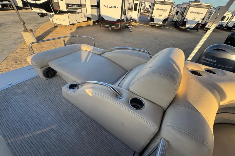Slide: The Image of 2010 Bennington 2375RL boat interior with beige seating and cup holders, parked near RVs. - 16