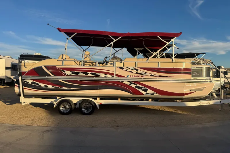 Slide: The Image of 2010 Bennington 2375RL pontoon boat with vibrant red and black graphics on a trailer. - 21
