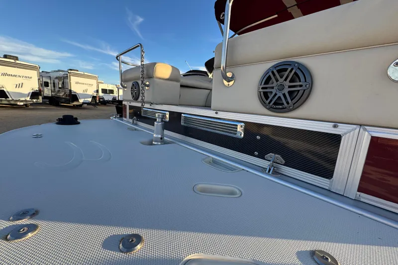 Slide: The Image of 2010 Bennington 2375RL boat deck with speaker, parked near RVs under clear sky. - 4