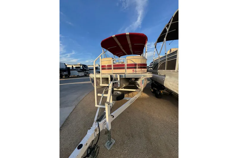 Slide: The Image of 2010 Bennington 2375RL pontoon boat with red canopy on trailer under blue sky. - 7