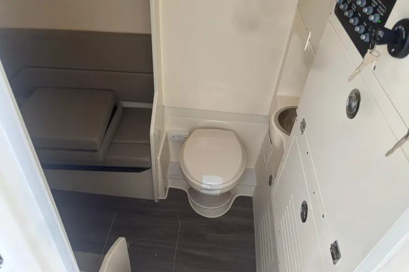 Slide: The Image of Interior of 2026 Scout 330 LXF boat featuring a compact bathroom with toilet and seating area. - 25