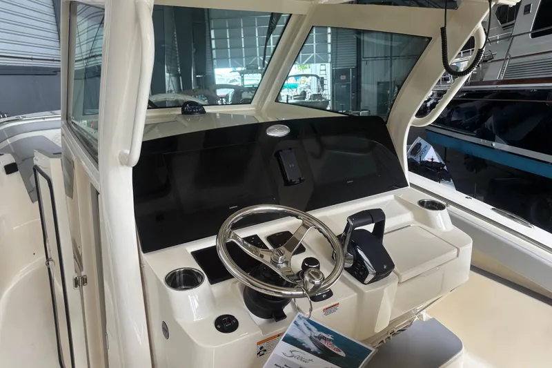 Slide: The Image of 2026 Scout 330 LXF boat cockpit with steering wheel and control panel in a showroom. - 12