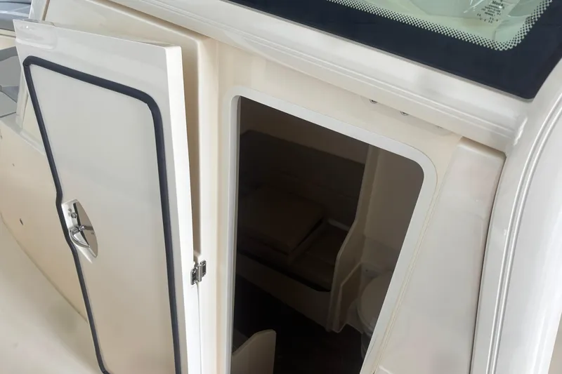 Slide: The Image of Open cabin door of 2026 Scout 330 LXF boat, revealing interior seating area. - 24