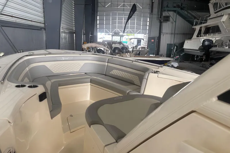 Slide: The Image of 2026 Scout 330 LXF boat interior with cushioned seating in a showroom. - 18