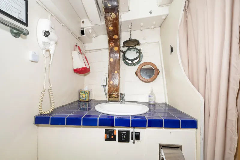 Slide: The Image of A sink with blue tiles, a porthole, and a wall-mounted phone. - 57
