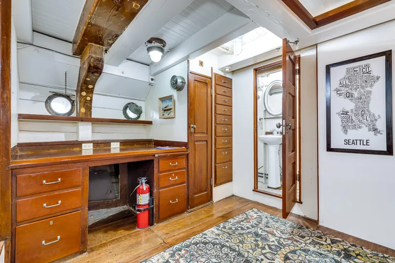 Slide: The Image of Interior of a boat with wooden furniture, a rug, and a small bathroom. - 50