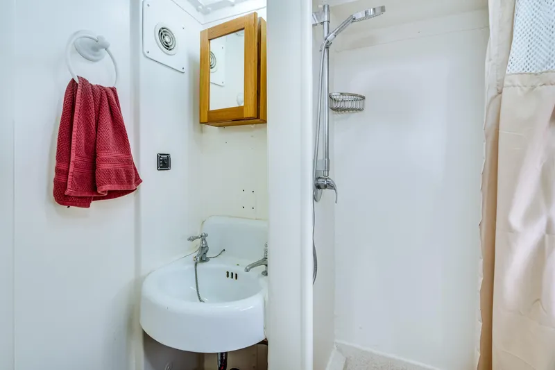 Slide: The Image of A bathroom with a sink, mirror, shower, and red towels. - 55