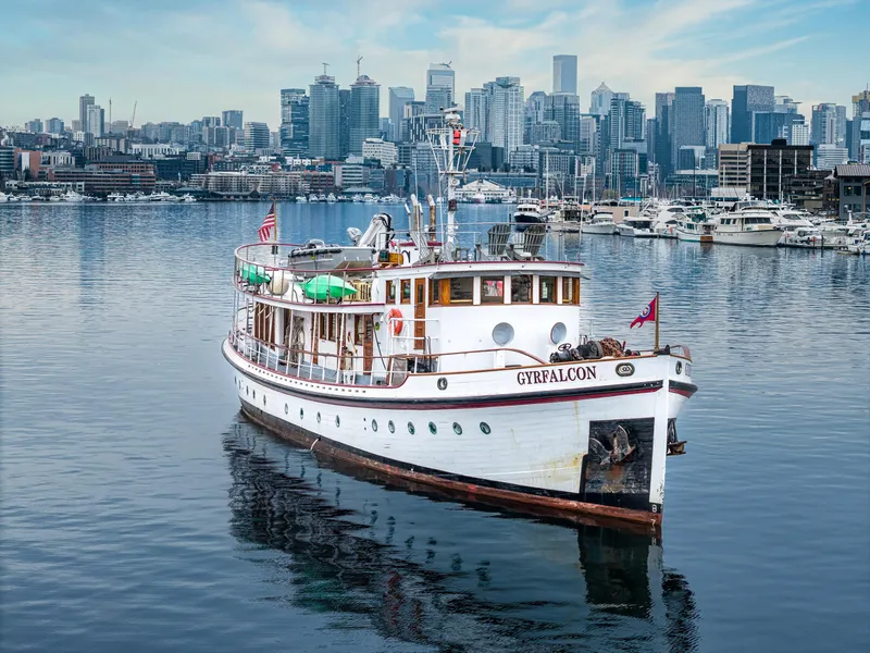Slide: The Image of Vintage 1941 Sagstad Fantail boat on calm water with city skyline in background. - 8