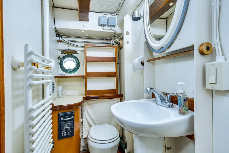 Slide: The Image of A classic boat bathroom with a sink, toilet, and porthole. - 53