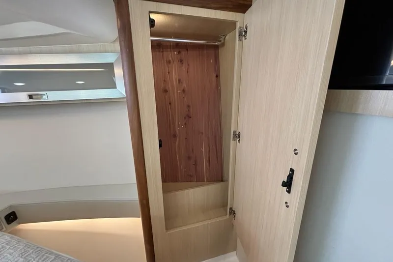 Slide: The Image of Open wooden closet inside 2026 Regal 36 XO boat cabin, showcasing interior design. - 54