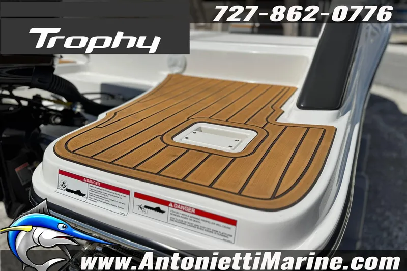 Slide: The Image of 2026 Bayliner Trophy T20CC boat deck with wood finish, contact info, and logo. - 7