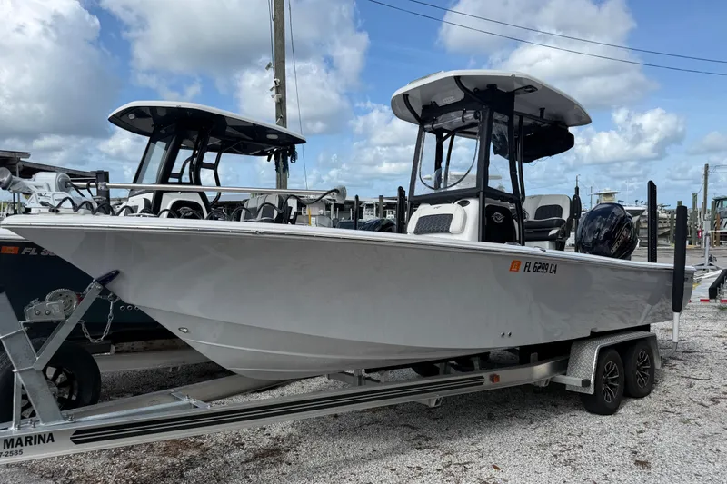 The Image of 2025 Tidewater 2300 Carolina Bay boat on trailer, parked at marina under cloudy sky. - 1
