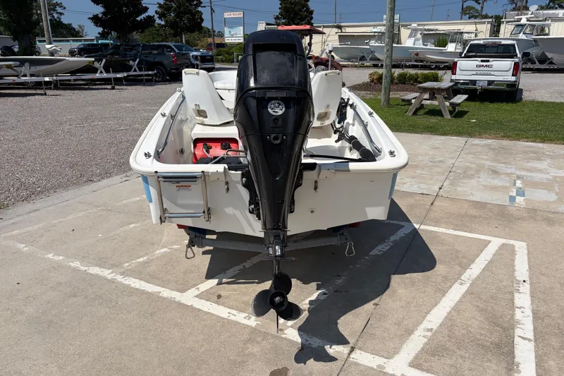 Slide: The Image of 2011 Boston Whaler 130 Super Sport boat with outboard motor in a parking lot. - 4