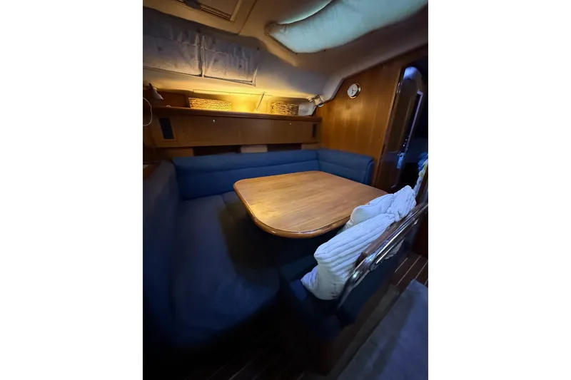 Slide: The Image of Cozy interior of 2004 Hunter 466 sailboat with wooden table and blue seating. - 16