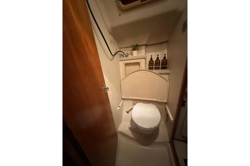 Slide: The Image of Compact bathroom in a 2004 Hunter 466 yacht, featuring a toilet and storage shelves. - 24