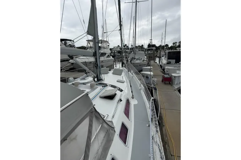 Slide: The Image of 2004 Hunter 466 sailboat docked at marina, showcasing deck and rigging. - 5