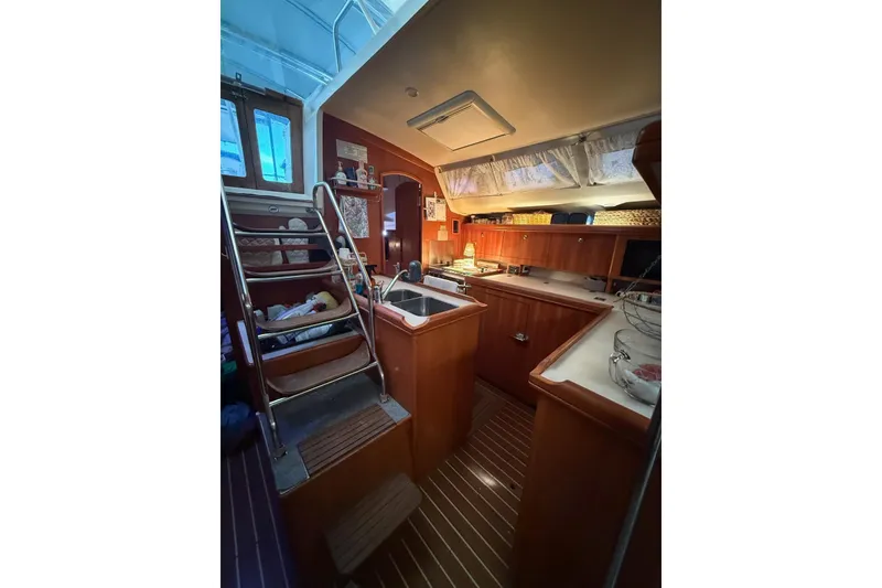 Slide: The Image of Interior of 2004 Hunter 466 sailboat with wooden cabinetry and compact kitchen area. - 12