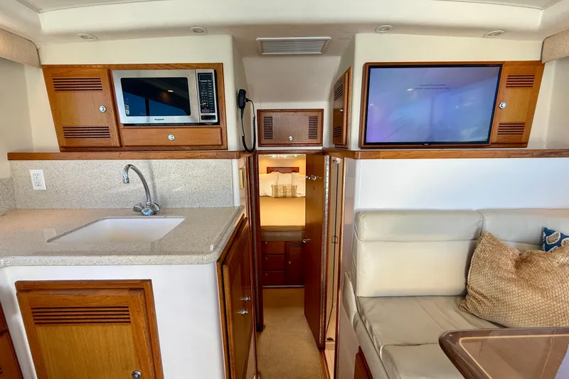 Slide: The Image of 2004 Cabo 35 Flybridge interior with kitchenette, sink, microwave, and cozy seating area. - 25