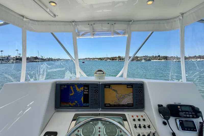 Slide: The Image of 2004 Cabo 35 Flybridge helm with navigation screens, steering wheel, and ocean view. - 45