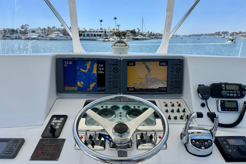 Slide: The Image of Helm of 2004 Cabo 35 Flybridge with navigation screens and controls, overlooking marina. - 35
