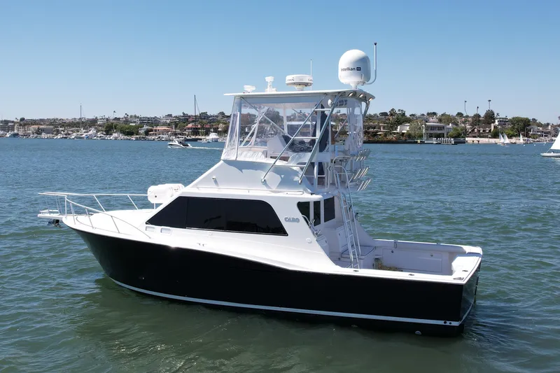 Slide: The Image of 2004 Cabo 35 Flybridge boat on calm water, showcasing sleek design and spacious deck. - 2