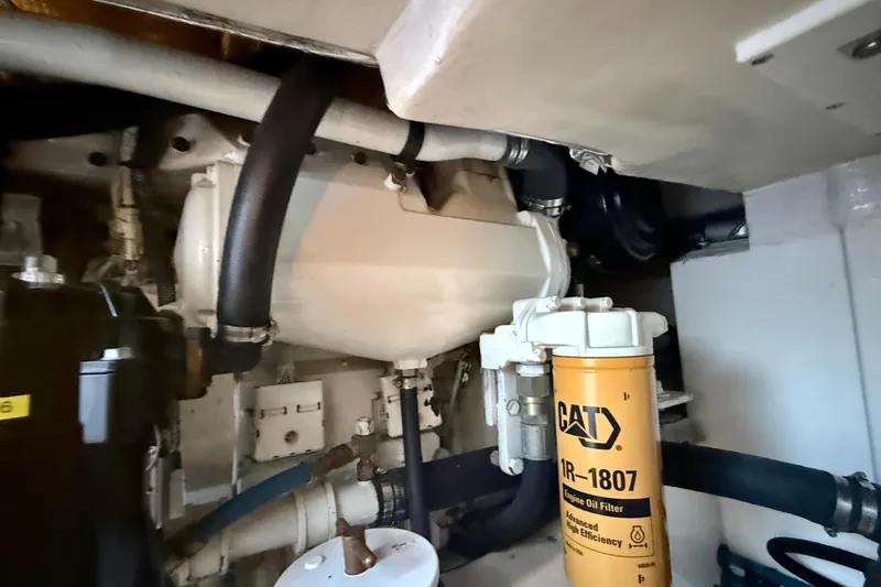 Slide: The Image of Engine room of 2004 Cabo 35 Flybridge with CAT oil filter and hoses visible. - 73