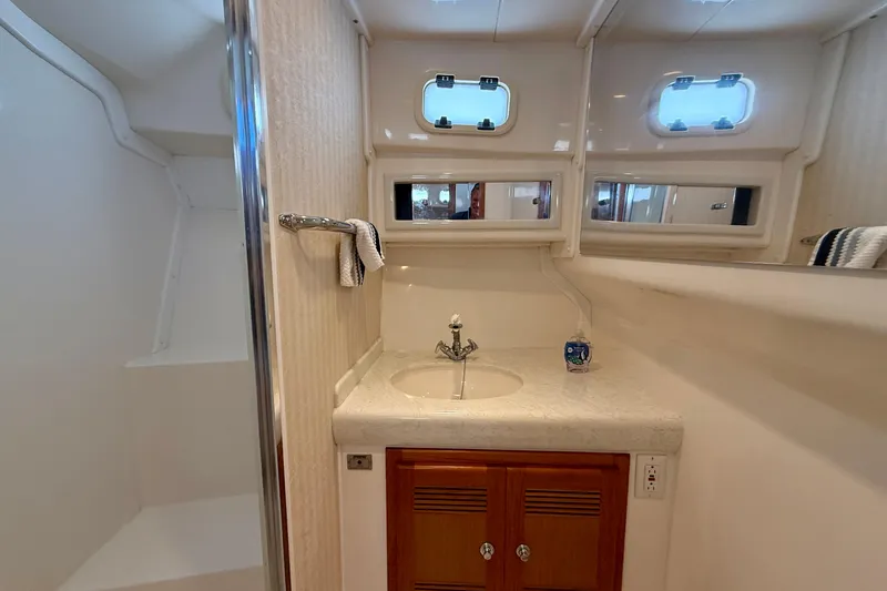 Slide: The Image of 2004 Cabo 35 Flybridge bathroom with sink, mirror, and shower area. - 16