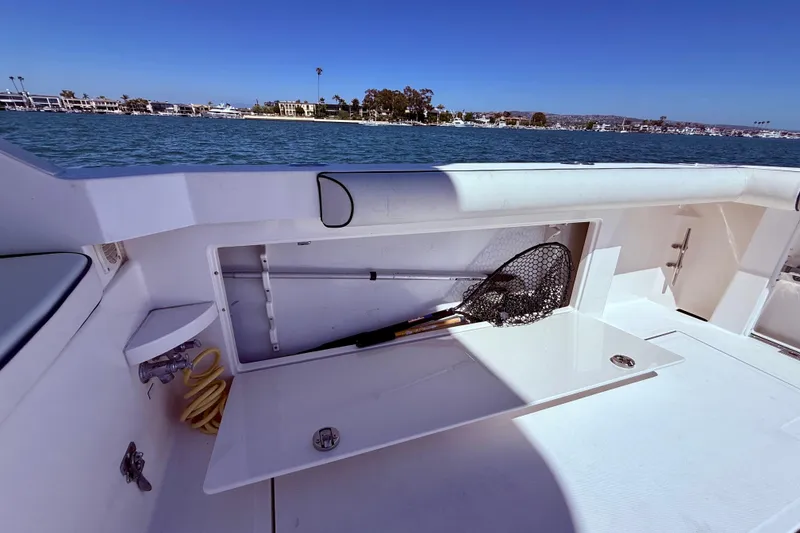 Slide: The Image of 2004 Cabo 35 Flybridge boat with open storage compartment and fishing net, docked by the water. - 55