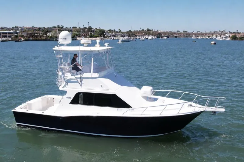 The Image of 2004 Cabo 35 Flybridge boat cruising on a calm waterway under clear skies. - 0