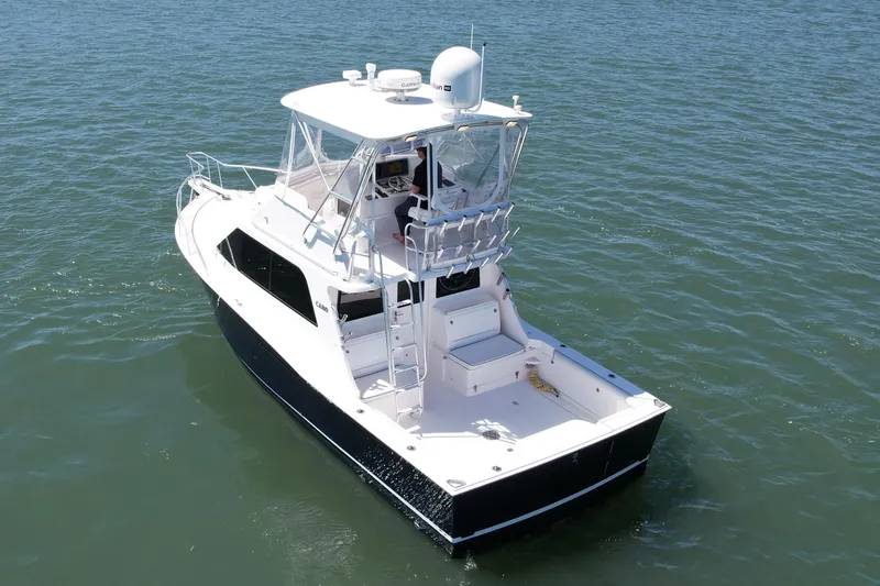 Slide: The Image of 2004 Cabo 35 Flybridge boat on calm water, showcasing sleek design and spacious deck. - 3