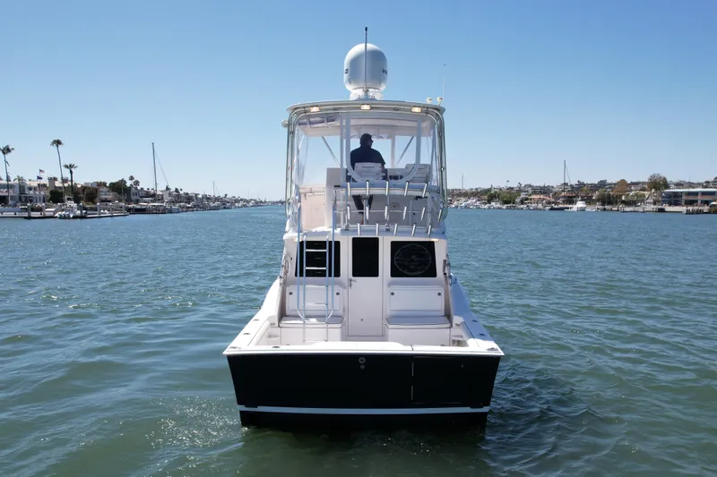 Slide: The Image of 2004 Cabo 35 Flybridge boat cruising on a sunny day in a scenic harbor. - 4