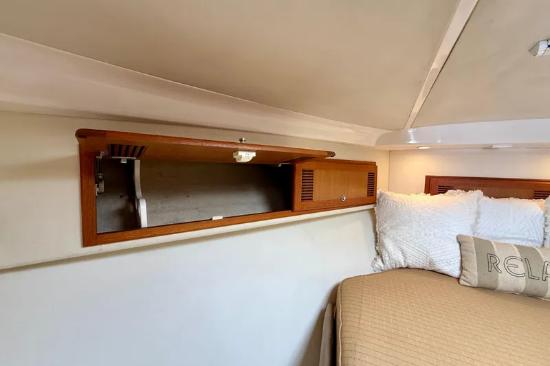 Slide: The Image of Interior of 2004 Cabo 35 Flybridge with open wooden cabinet and cozy bedding. - 14