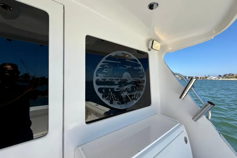 Slide: The Image of 2004 Cabo 35 Flybridge boat with decorative window art, docked by the water. - 49