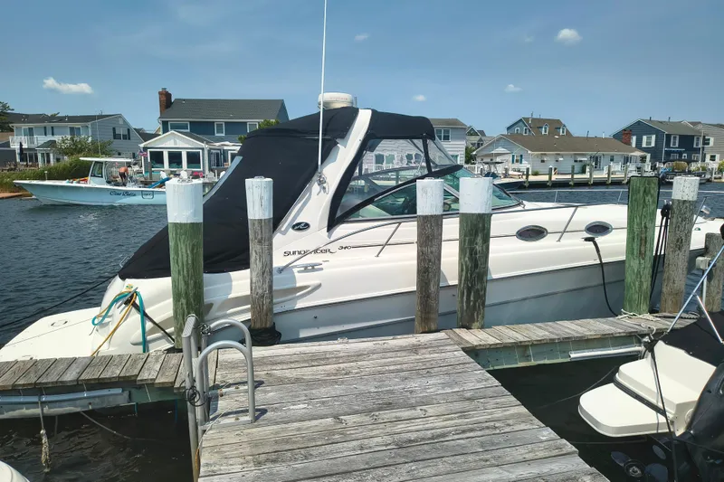 The Image of 2001 Sea Ray 340 Sundancer docked at a marina with waterfront homes in the background. - 1