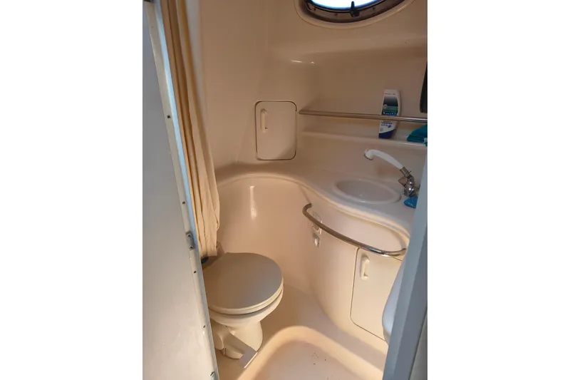 Slide: The Image of 2001 Sea Ray 340 Sundancer bathroom with toilet, sink, and porthole window. - 14