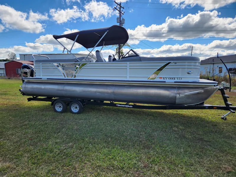 Slide: The Image of A 2019 Veranda VTX 25RC pontoon boat on a trailer in a grassy area. - 1