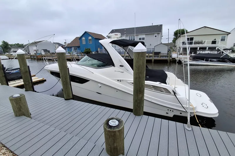 The Image of 2016 Sea Ray Sundancer 330 docked at a marina, surrounded by waterfront homes. - 0