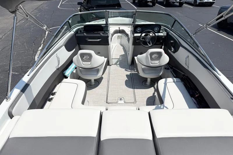 Slide: The Image of 2023 Crownline 240 SS boat interior with seating and steering wheel in a parking lot. - 6