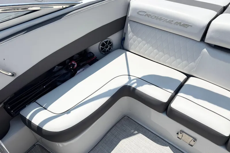 Slide: The Image of 2023 Crownline 240 SS boat interior with white cushioned seating and storage compartment. - 11