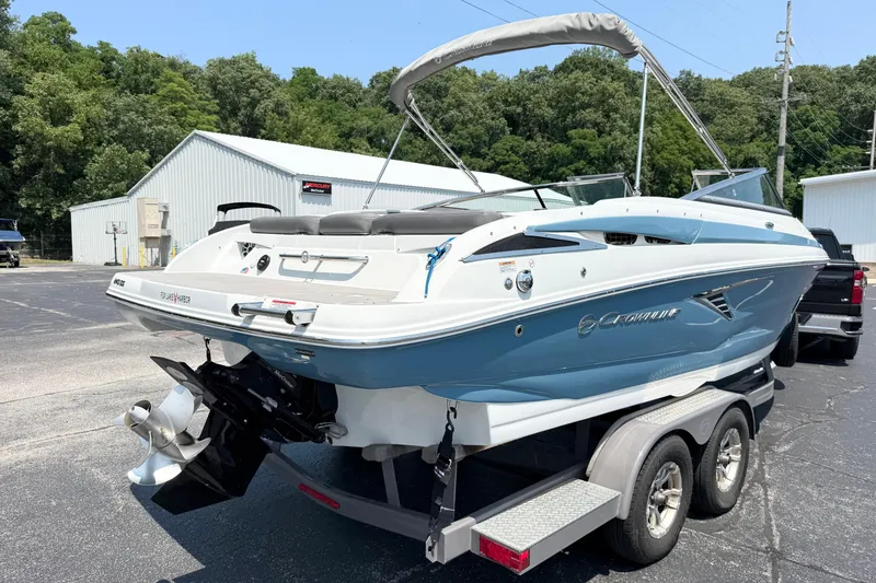Slide: The Image of 2023 Crownline 240 SS boat on trailer, blue and white design, parked outdoors. - 2
