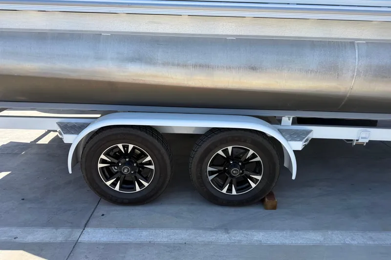 Slide: The Image of Trailer wheels of a 2022 South Bay 224CR2 pontoon boat on pavement. - 18