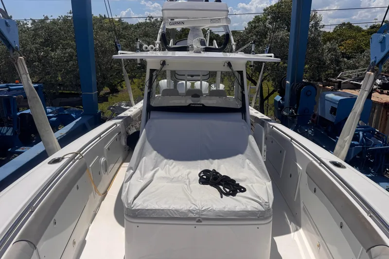 Slide: The Image of 2016 Everglades 435 Center Console boat with covered seating, docked under blue sky. - 26