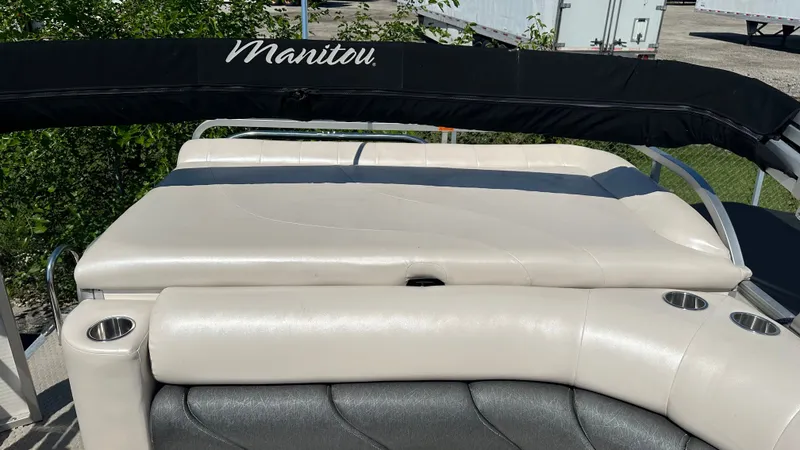 Slide: The Image of The image shows the rear of a Manitou Legacy pontoon boat with beige upholstery and cup holders. - 7
