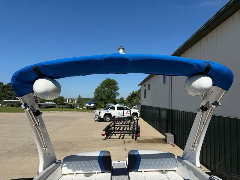 Slide: The Image of A 2019 Regal 23 RX Bowrider with a blue bimini top, parked on a trailer. - 16